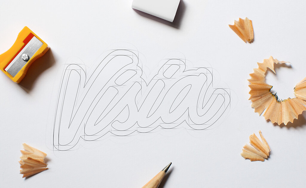 Potloodschets van het woord "Visia", omringd door een gum, een puntenslijper en potloodspaanders op een wit oppervlak, ter illustratie van een lopende creatieve rebrandingstrategie.