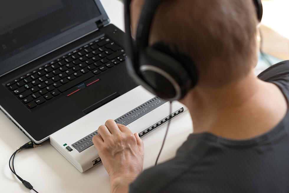 Persoon die werkt met een braille toetsenbord