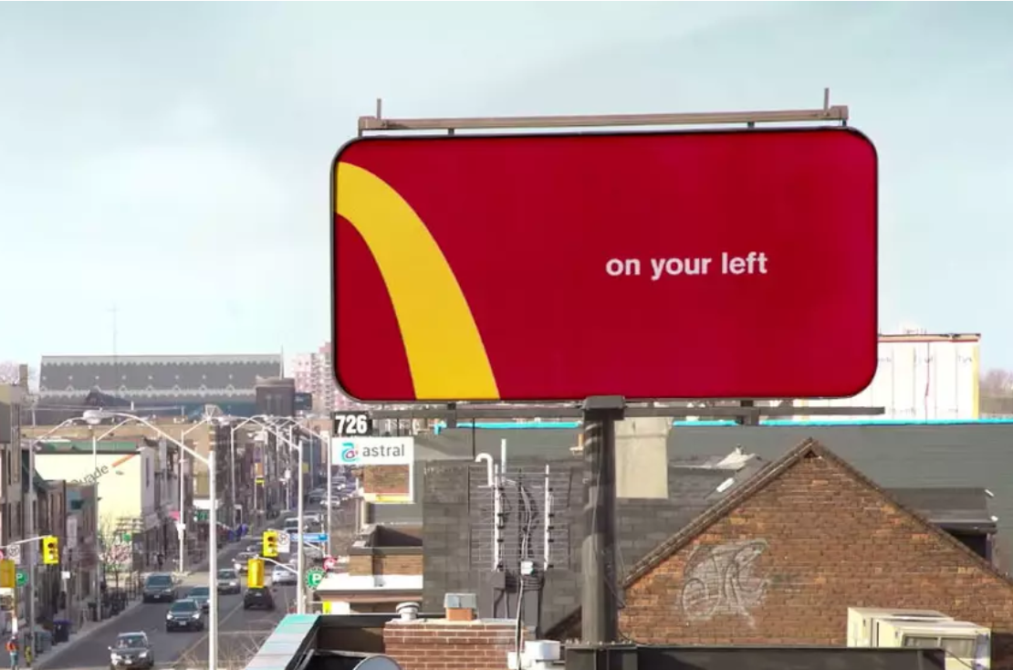 voorbeeld goede soort marketing. groot reclamebord bij een weg. met een deel van het mc donalds logo en 'on your left' erop.