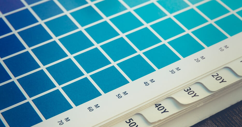 Close-up van een kleurstalenboek met verschillende tinten blauw met gelabelde secties en tabbladen aan de rechterkant, ideaal voor kleurgebruik in huisstijlen.