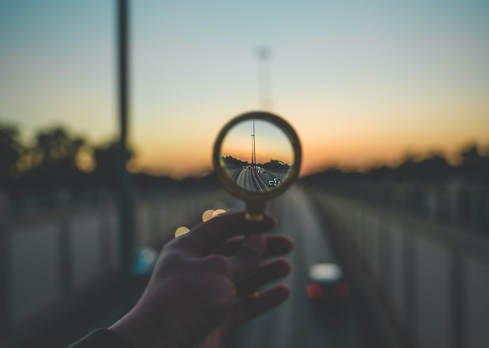 person holding magnifying glass during sunset