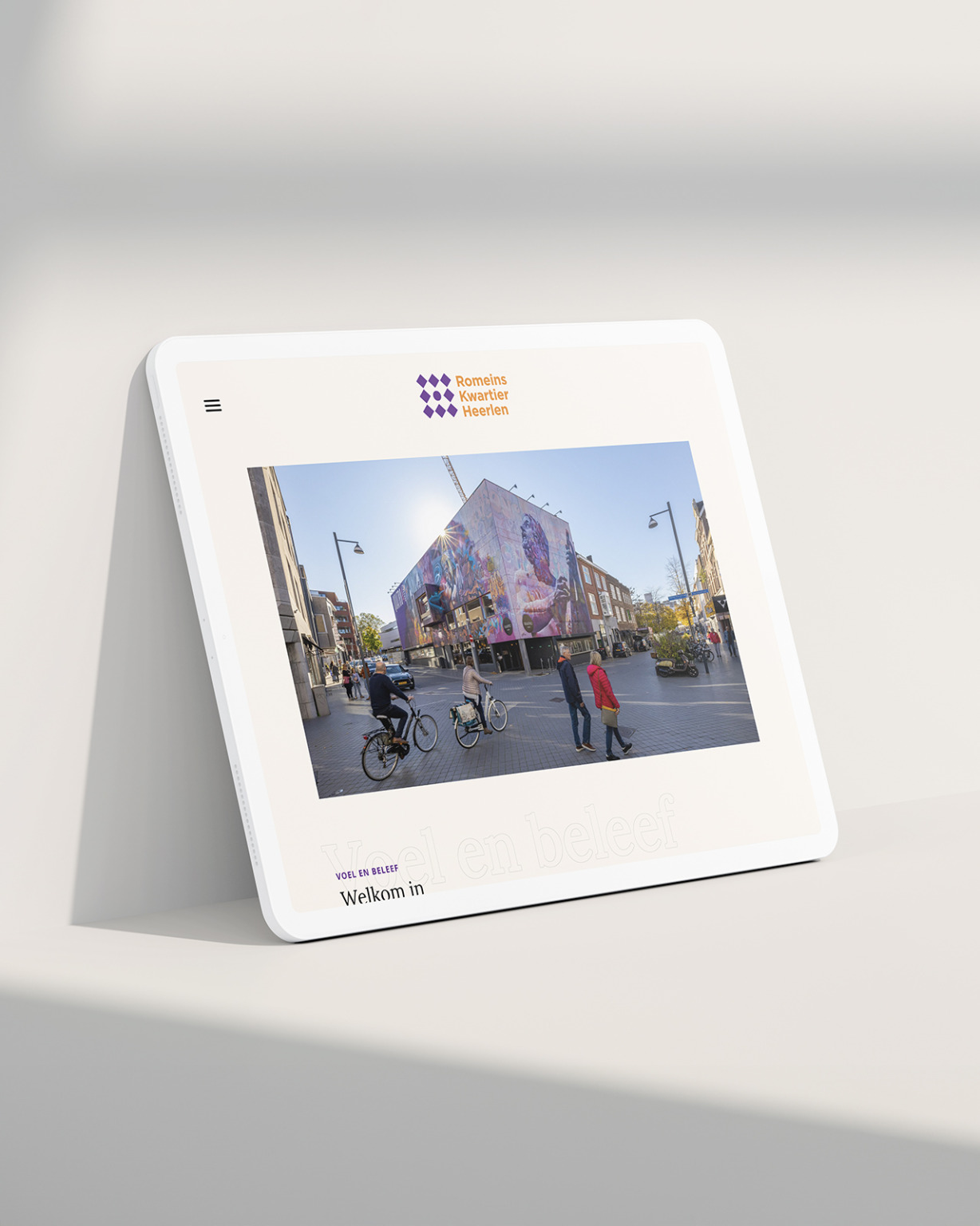 Tablet met een muurschildering uit het Heerlense Romeins Kwartier op het scherm, geplaatst op een wit oppervlak met een zachte schaduw.