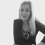 Zwart-witfoto van een vrouw met lang blond haar, gekleed in een blazer en een topje met patroon, die zelfverzekerd naar de camera kijkt. Het modestatement dat ze maakt met Moveoo is zowel opvallend als tijdloos.