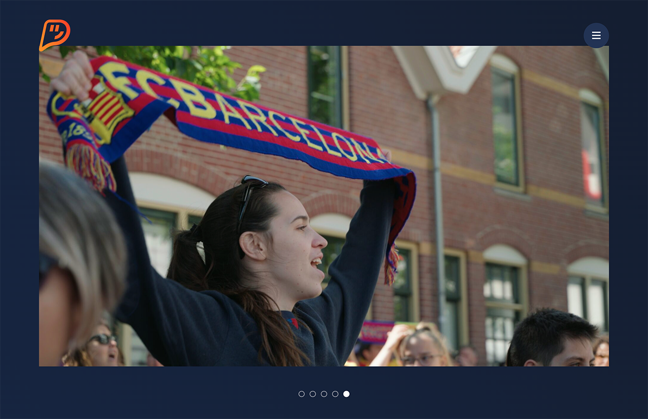 Een juichende fan met een 'FC Barcelona'-sjaal, omringd door andere fans buiten een bakstenen gebouw, creëert een sfeer die lijkt op die van De Plaatjesmakers, die de vurigheid van een speeldag illustreert.