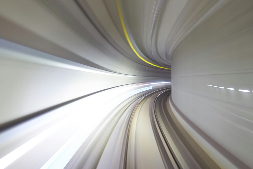 Een snelle weergave van een futuristische, gebogen tunnel met lichtstrepen die een gevoel van snelle beweging en snelheid creëren, wat de ervaring van het navigeren op een langzaam ladende website contrasteert.