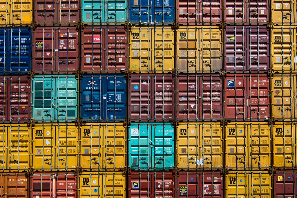 Gestapelde kleurrijke zeecontainers in verschillende tinten geel, rood, blauw en groen, gerangschikt in een rasterpatroon, lijken op een goed georganiseerd cachesysteem voor websites.
