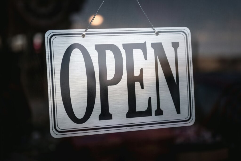 Een bordje met "OPEN" op een glazen deur nodigt klanten uit om binnen te komen en draagt op subtiele wijze bij aan de lokale SEO-verbetering, omdat de aandacht wordt gevestigd op de gastvrije sfeer van het bedrijf.