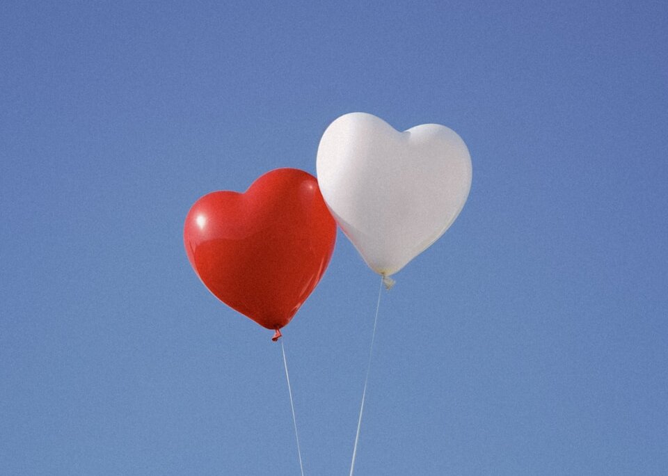 two heart shaped balloons floating in the air
