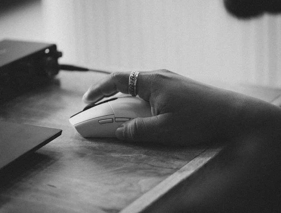 Person's hand using a computer mouse on a desk.