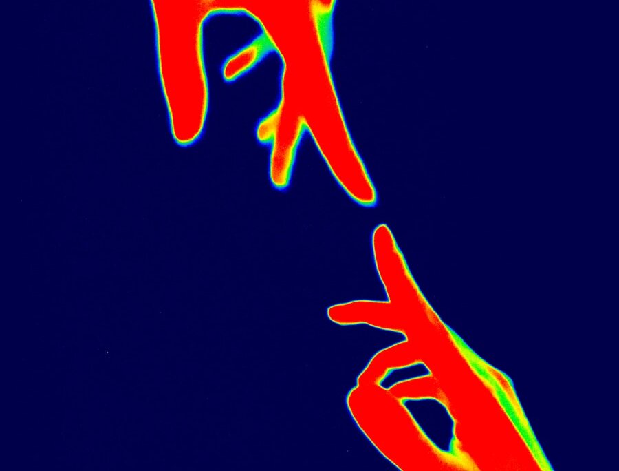 Two hands reaching out against dark background