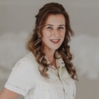 Een glimlachende vrouw in een wit overhemd met kraag, gespecialiseerd in belastingadvies.