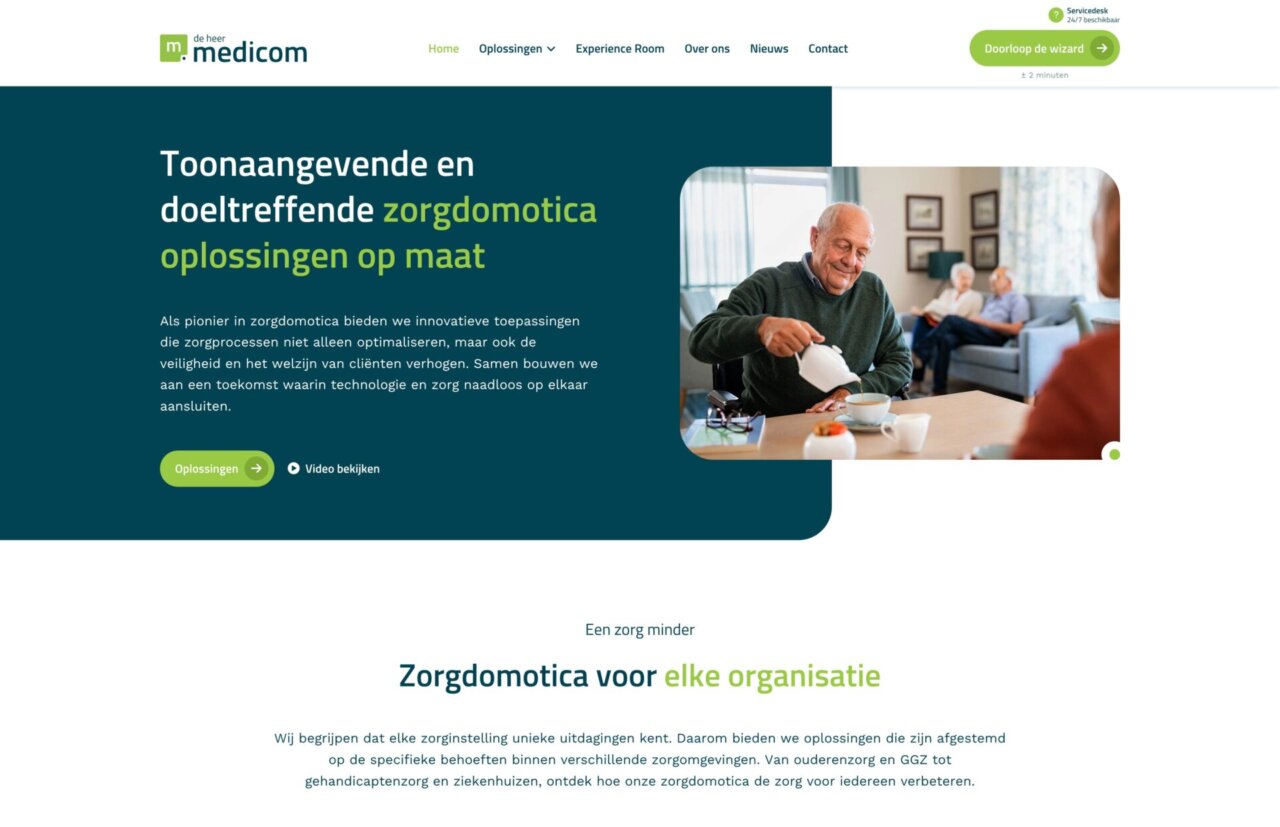 Een lachende oudere man eet soep aan een tafel, met twee mensen zittend en pratend op de achtergrond.