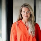 Een portret van een vrouw in een oranje overhemd met knopen voor Mertens Communications.